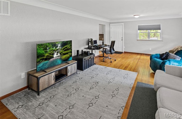 living room with crown molding, wood finished floors, baseboards, and a desk