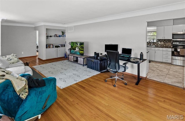 office area with crown molding and light wood finished floors