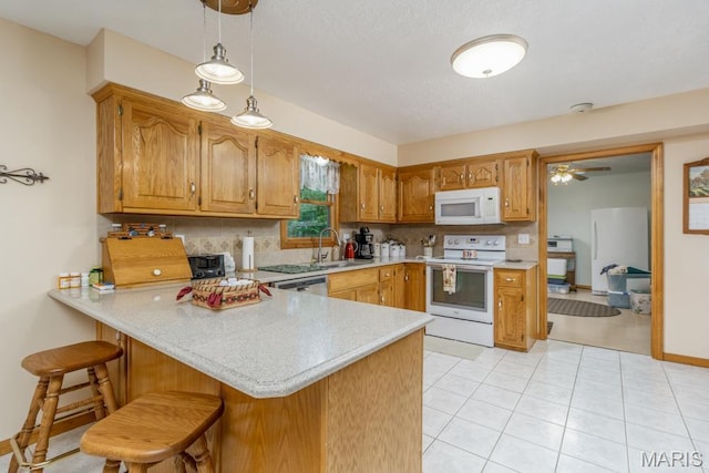 kitchen with white appliances, a peninsula, decorative backsplash, light countertops, and a breakfast bar area