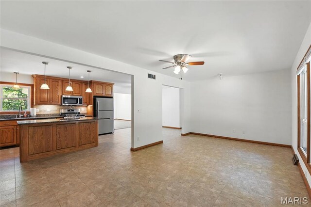 124 Dawn Dr, Washington, MO 63090 - kitchen featuring appliances with stainless steel finishes, brown cabinetry, dark countertops, and ceiling fan