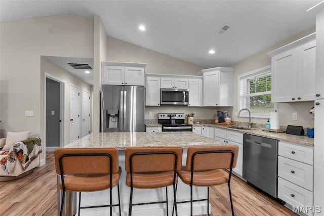 1111 Tulach Ard Ct, Jackson, MO 63755 - kitchen featuring stainless steel appliances, a sink, lofted ceiling, a center island, and white cabinets
