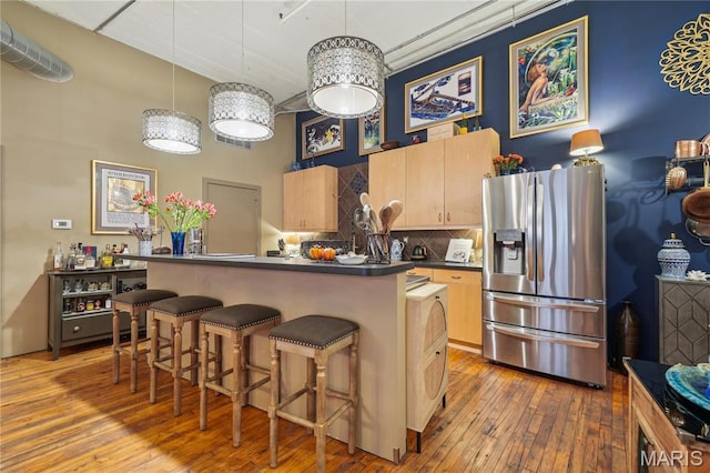 1010 Saint Charles St Unit 701, Saint Louis, MO 63101 - kitchen featuring stainless steel refrigerator with ice dispenser, dark countertops, backsplash, a kitchen bar, and wood-type flooring