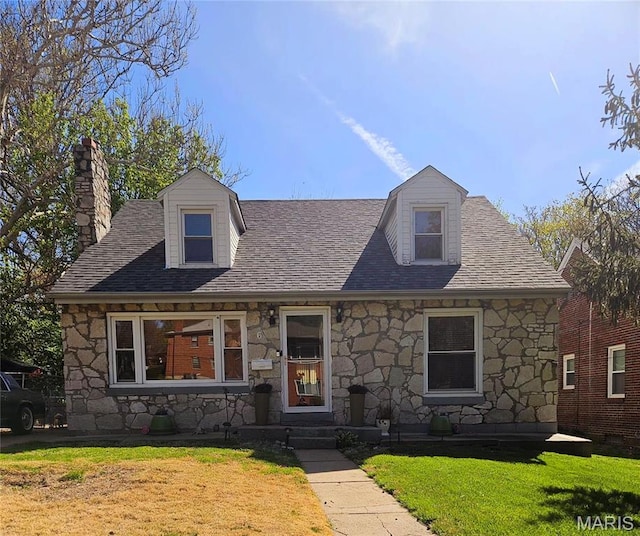 view of front of house with stone siding, a chimney, a front yard, and roof with shingles