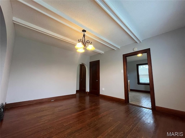 213 W Broadway, Trenton, IL 62293 - unfurnished room featuring arched walkways, wood finished floors, a chandelier, beam ceiling, and baseboards
