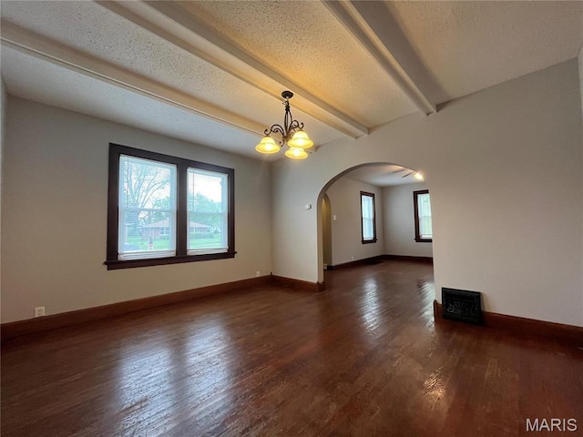 213 W Broadway, Trenton, IL 62293 - empty room with arched walkways, wood finished floors, beamed ceiling, baseboards, and a chandelier