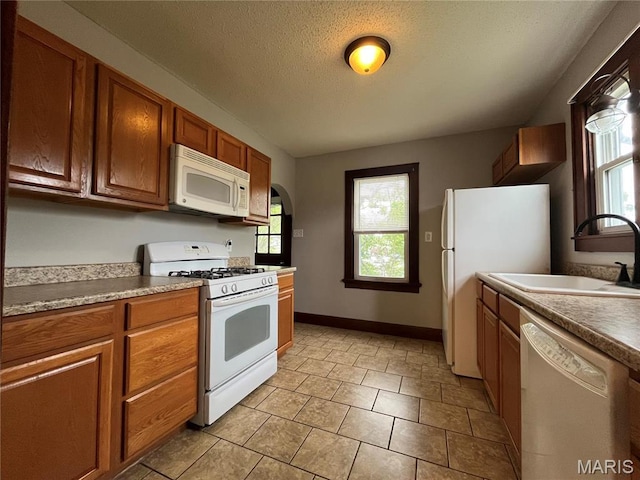 213 W Broadway, Trenton, IL 62293 - kitchen featuring white appliances, a sink, plenty of natural light, brown cabinets, and a textured ceiling