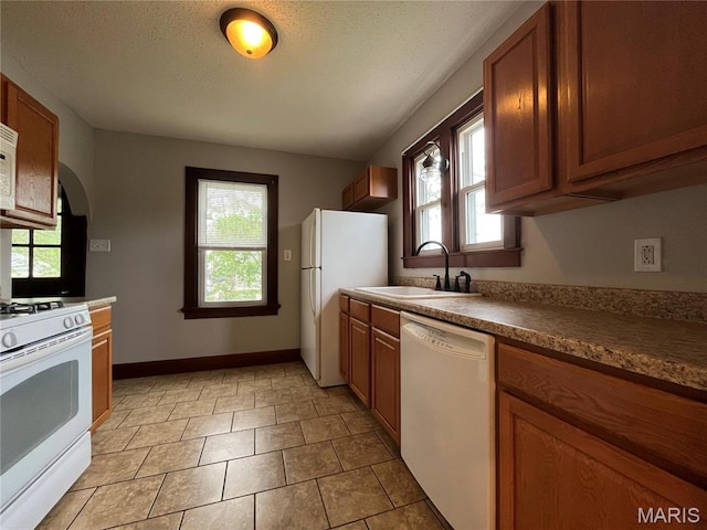 213 W Broadway, Trenton, IL 62293 - kitchen featuring a sink, white appliances, brown cabinetry, and arched walkways