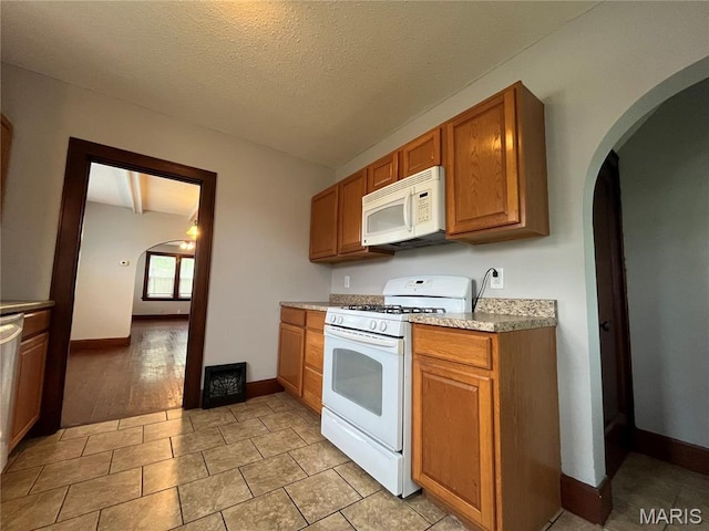 213 W Broadway, Trenton, IL 62293 - kitchen featuring white appliances, arched walkways, brown cabinetry, baseboards, and a textured ceiling
