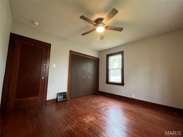 213 W Broadway, Trenton, IL 62293 - unfurnished bedroom with dark wood-style flooring, a closet, baseboards, and a ceiling fan