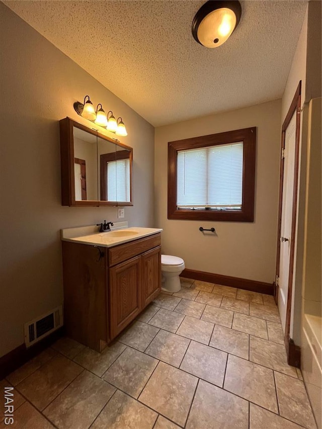 213 W Broadway, Trenton, IL 62293 - full bath with a textured ceiling, vanity, toilet, tile patterned flooring, and baseboards