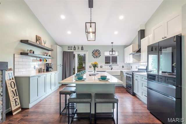 159 Village Circle Dr, Lake St Louis, MO 63367 - kitchen featuring appliances with stainless steel finishes, lofted ceiling, tasteful backsplash, wall chimney exhaust hood, and a center island