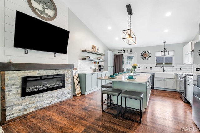 159 Village Circle Dr, Lake St Louis, MO 63367 - kitchen featuring gas stove, vaulted ceiling, a center island, decorative backsplash, and light countertops
