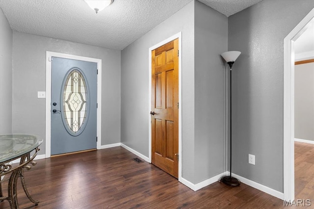 entrance foyer featuring dark wood-type flooring, a textured ceiling, and baseboards