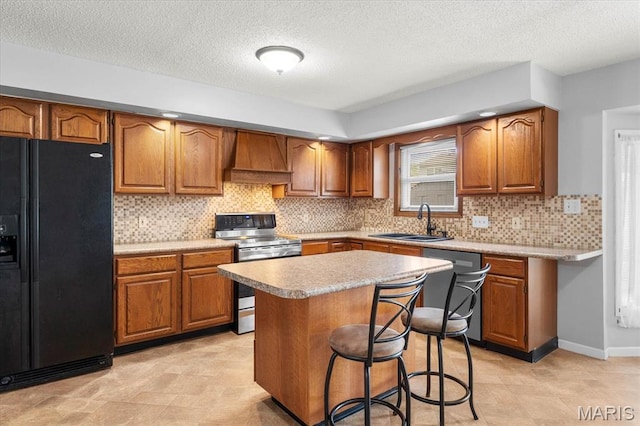 kitchen featuring appliances with stainless steel finishes, a sink, custom range hood, brown cabinets, and light countertops