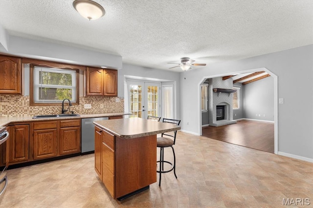 kitchen with dishwasher, a sink, ceiling fan, a breakfast bar area, and a kitchen island