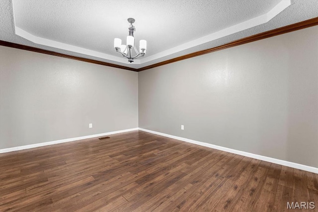 unfurnished room with a tray ceiling, a chandelier, a textured ceiling, dark wood finished floors, and baseboards