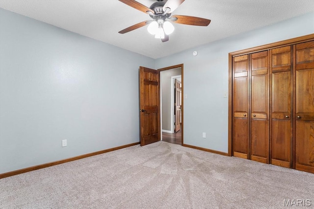 unfurnished bedroom with carpet, baseboards, a closet, and ceiling fan