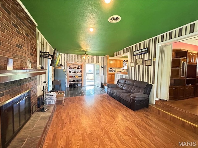 120 E Beth St, Licking, MO 65542 - living room featuring wood finished floors, a brick fireplace, and wallpapered walls