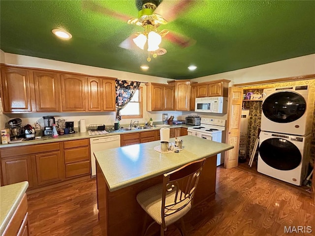 120 E Beth St, Licking, MO 65542 - kitchen with white appliances, stacked washer and clothes dryer, a sink, a breakfast bar area, and dark wood-type flooring