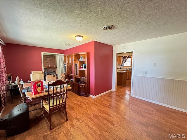 120 E Beth St, Licking, MO 65542 - dining space featuring light wood-style floors, a wainscoted wall, and a textured ceiling