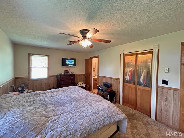 120 E Beth St, Licking, MO 65542 - carpeted bedroom featuring wainscoting, wooden walls, a textured ceiling, a ceiling fan, and ensuite bathroom