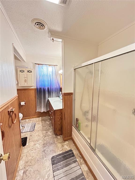120 E Beth St, Licking, MO 65542 - full bathroom with a wainscoted wall, a textured ceiling, toilet, wood walls, and shower / bath combination with glass door