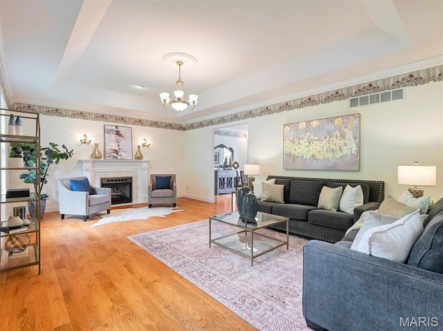 590 Fairway Dr, Union, MO 63084 - living area with a raised ceiling, a chandelier, baseboards, light wood-style floors, and a glass covered fireplace
