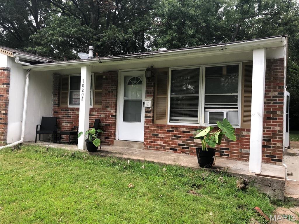 10208 Royal Dr, Saint Louis, MO 63136 - view of front of house with brick siding, a front lawn, covered porch, and cooling unit