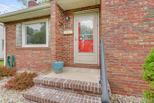 doorway to property with brick siding and a chimney