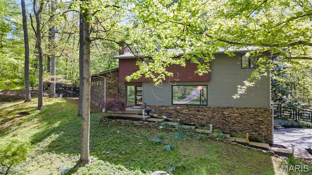 view of property exterior featuring stone siding, a lawn, and a chimney