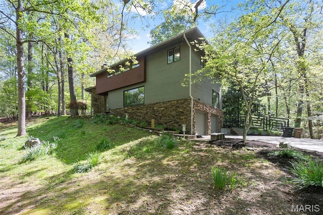 view of property exterior featuring an attached garage, stone siding, and concrete driveway