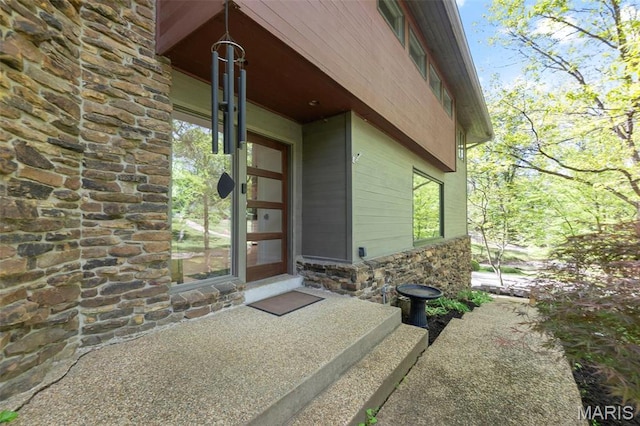 view of exterior entry featuring stone siding and a porch
