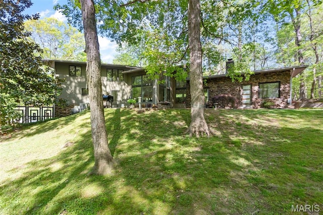 back of property with a lawn, a chimney, and a sunroom