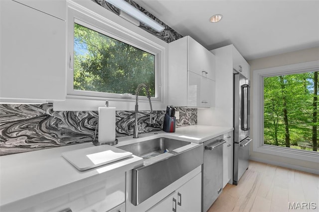 kitchen featuring stainless steel appliances, light countertops, white cabinetry, and light wood-type flooring