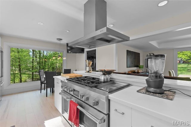 kitchen featuring high end stove, ventilation hood, white cabinets, light countertops, and recessed lighting