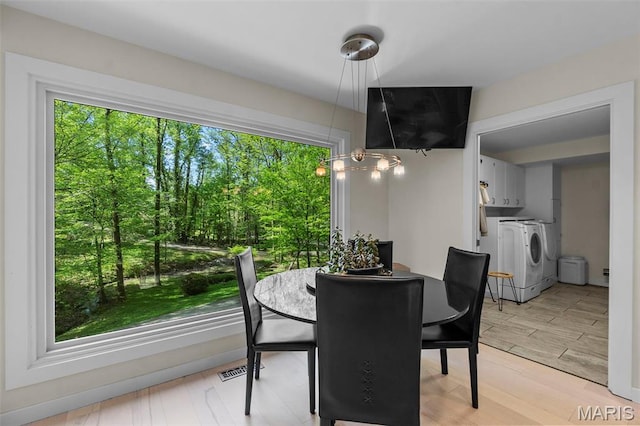 dining space with washer and clothes dryer, healthy amount of natural light, and light wood-type flooring