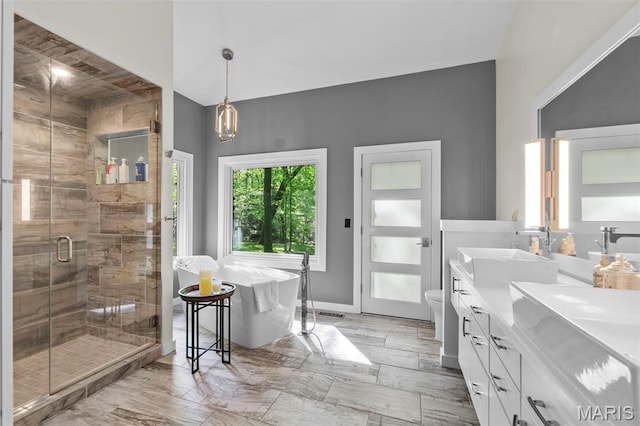full bathroom with a shower stall, toilet, double vanity, a freestanding tub, and marble look tile flooring