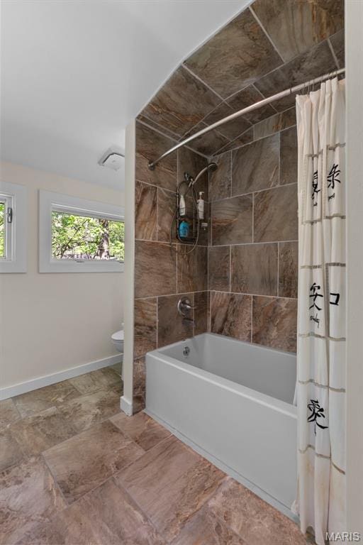 full bathroom with shower / bath combo with shower curtain, healthy amount of natural light, baseboards, and toilet
