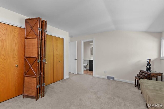 unfurnished bedroom with carpet flooring, baseboards, vaulted ceiling, and ensuite bath