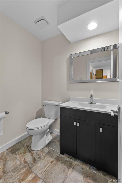bathroom with toilet, baseboards, and vanity