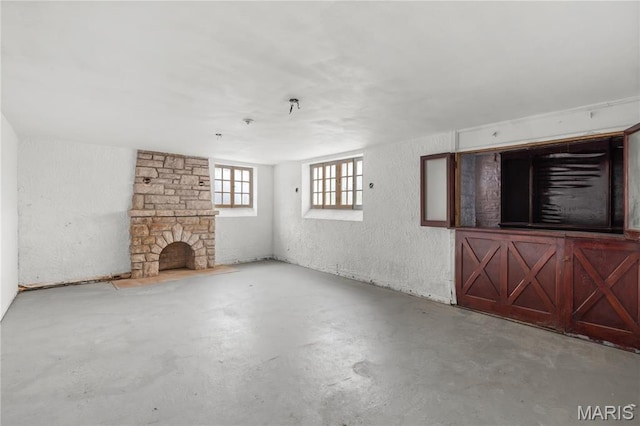 7280 S Roland Blvd, Saint Louis, MO 63121 - unfurnished living room with concrete flooring, a textured wall, and a stone fireplace