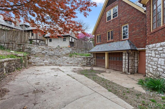 7280 S Roland Blvd, Saint Louis, MO 63121 - view of property exterior featuring fence, an attached garage, and stone siding