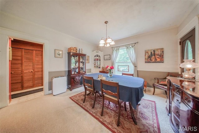 dining room with light carpet, a chandelier, and crown molding