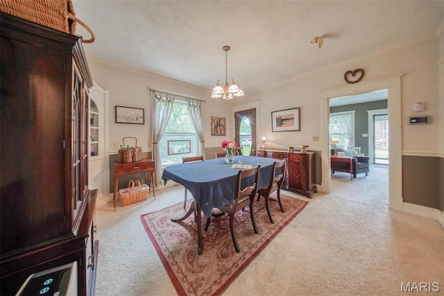 dining area with light carpet, a chandelier, and ornamental molding
