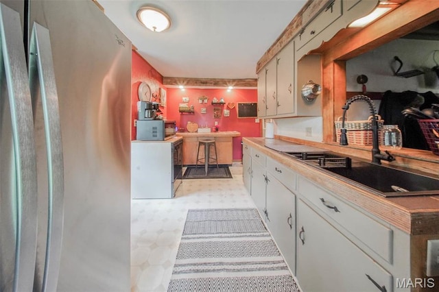kitchen with a sink, light flooring, light countertops, and stainless steel microwave
