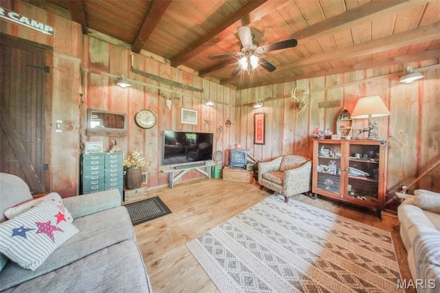 living area featuring wood ceiling, wood finished floors, beam ceiling, a ceiling fan, and wood walls