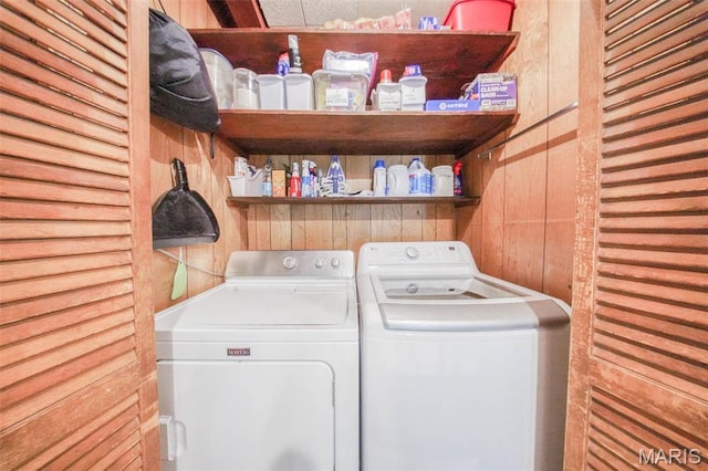 laundry area featuring washer and dryer and wood walls