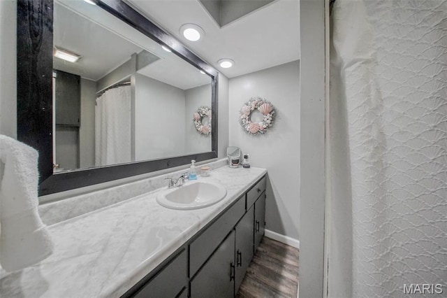 full bath with wood finished floors, vanity, and baseboards