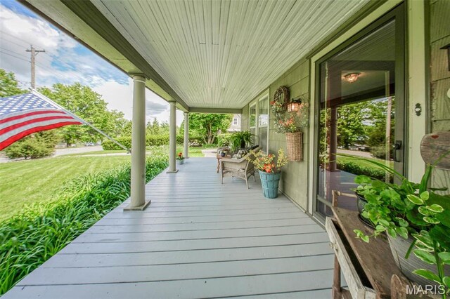 wooden terrace featuring a porch and a lawn