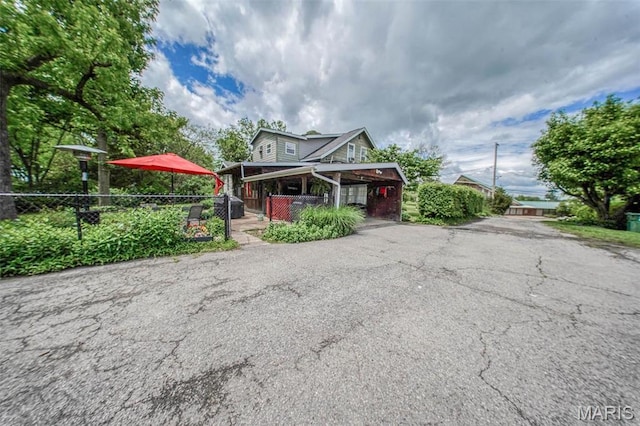 view of front of home featuring fence and asphalt driveway